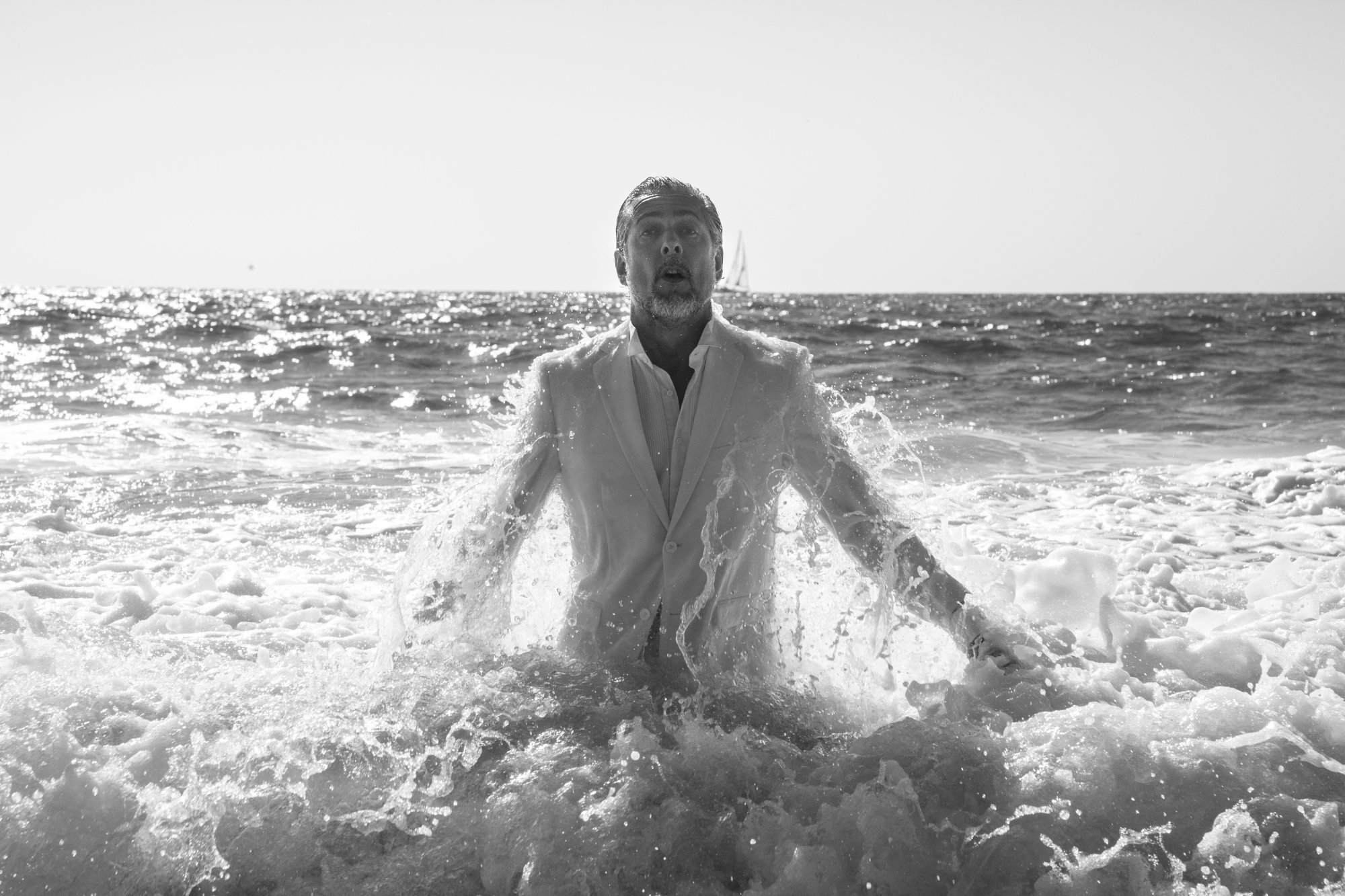 Alexander Braam emerging from the ocean in a white suit